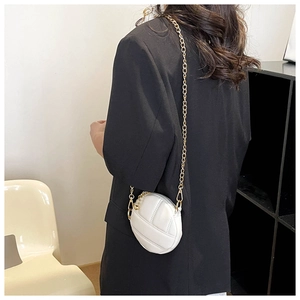 Gros plan d'un mini sac à bandoulière rond blanc matelassé avec détail chaîne dorée