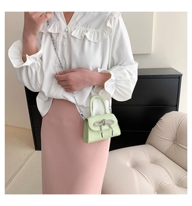 Detail of mint green mini crossbody bag with delicate silver wire bow and chain strap