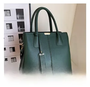 Detail of dark green litchi grain tote bag with gold hardware and decorative tag