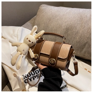 Close-up of quilted two-tone handbag with metal double twist-lock and plush bunny charm