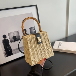 Handwoven straw bag with bamboo handle, black leather flap and golden twist lock