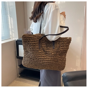 Detail of dark brown woven straw tote bag with premium leather straps and zipper closure