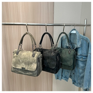 Detail view of retro suede tote bags in grey, black and green with chain straps