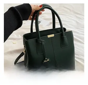 Detail shot of dark green lychee pattern handbag with golden hardware and handles