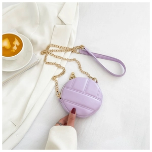 Gros plan du petit sac rond matelassé lavande avec chaîne dorée sur blazer blanc chic