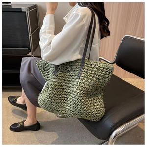 Detailed view of handwoven grass green straw tote bag with brown leather shoulder straps