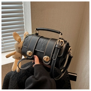 Detail of black cylinder bag with diamond stitching and beige plush bunny charm
