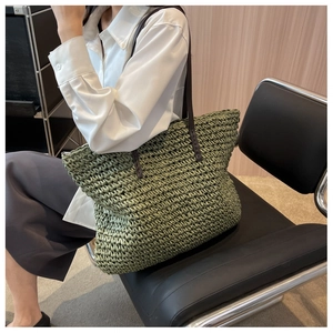 Close-up of green woven straw tote bag with brown leather handles on a modern chair