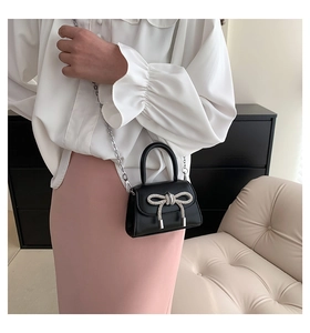 Detail of black mini crossbody bag with a sparkling silver rhinestone bow decoration
