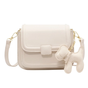 Minimalist cream white crossbody bag with gold hardware and puppy charm on white background