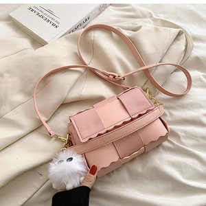 Detail of pink woven crossbody bag with wavy edge trim and soft plush charm accessory