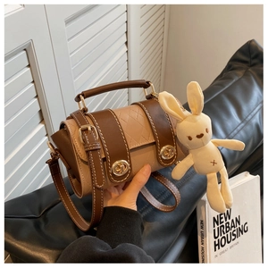 Detail of a vintage quilted messenger bag with turn-lock and plush bunny charm