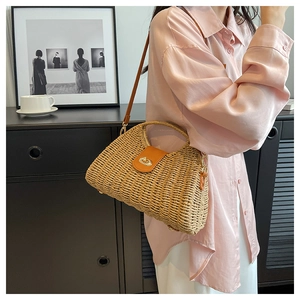 Detail der handgewebten Strohtasche mit brauner Lederklappe und goldenem Drehverschluss