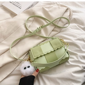 Detail of light green woven PU leather bag with wavy trim and plush ball charm