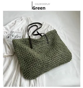 Close-up of green hand-woven straw tote bag with brown straps for summer beach vacation