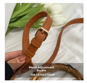 Detail of adjustable leather strap with gold hardware and bamboo handle on a woven bag