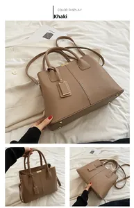 Detail view of khaki pebbled leather handbag with dual handles and metal studs