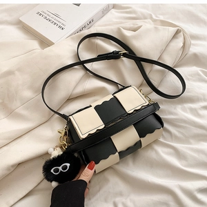 Chic black and white checkerboard crossbody bag with wavy flap and plush eyewear charm