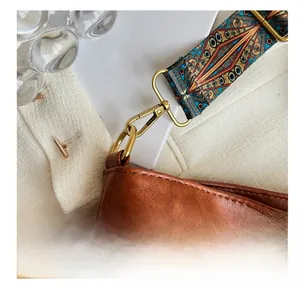 Detail of vintage brown leather bag with bohemian geometric woven shoulder strap