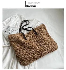 Detail view of brown woven straw tote bag with leather straps on a white background