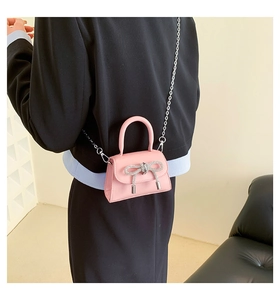 Close-up of pink mini crossbody bag with rhinestone bow and silver chain strap