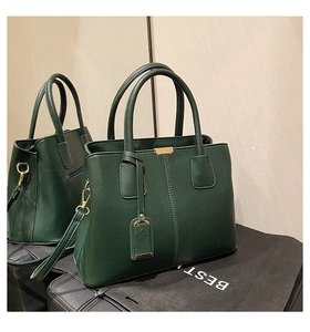Detail of dark green pebble leather tote bag with gold hardware and removable tag