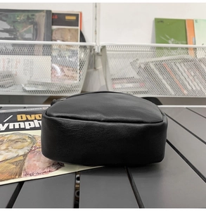 Detail view of the black leather crossbody bag showing smooth texture and metal zipper