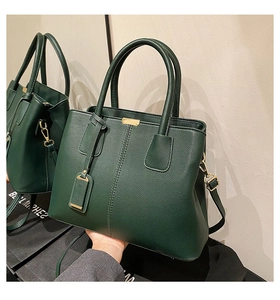 Detail of dark green lychee leather handbag with gold buckles and mirror reflection