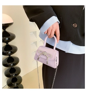 Detail of light purple PU leather mini bag with silver glitter bow and metal chain