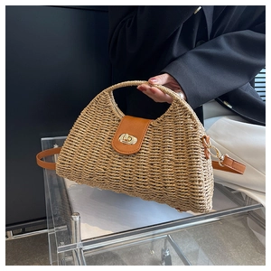 Detail der handgewebten Strohhandtasche mit brauner Lederklappe und goldenem Schloss