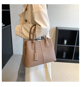 Taupe lychee textured tote bag with dual handles shown on a model in trench coat