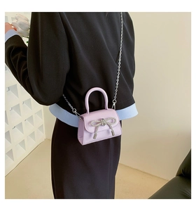 Lavender mini leather handbag with rhinestone bow detail and silver chain strap on model