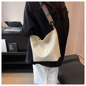 Detail of off-white hobo bag with ethnic print wide strap against office backdrop
