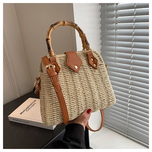 Detail of hand-woven straw bag featuring a bamboo top handle and gold twist-lock closure
