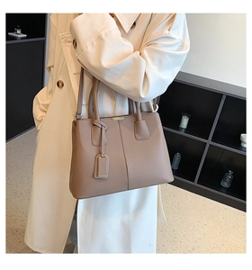 Chic lychee pattern tote bag in clay purple shown with adjustable strap on a beige trench coat