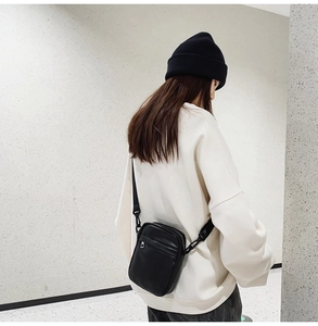 Minimalist black leather crossbody bag for women shown on shoulder for daily fashion use