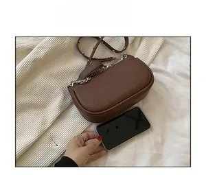 Size comparison of a vintage brown pebble leather bag with silver studs and a smartphone