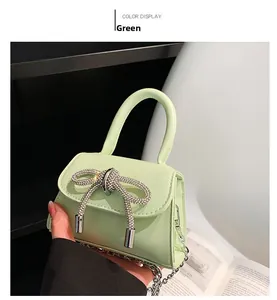 Detail of mint green mini handbag with rhinestone bow and metallic chain strap