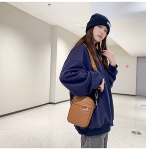 Detailed view of women's brown leather crossbody bag with adjustable strap worn by a model