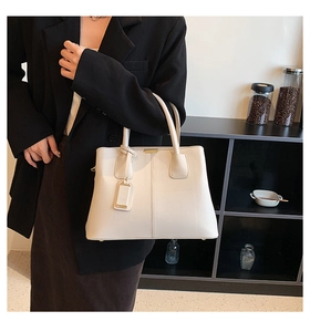 Close-up of beige lychee pattern leather tote bag with elegant metallic pendant detail