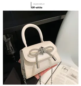 Detail showing the cream mini bag with a sparkling rhinestone bow and silver chain