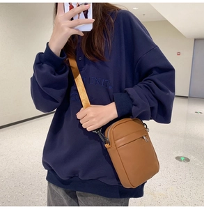 Brown crossbody phone bag with yellow strap and front zipper compartment detail