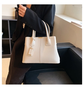 Chic beige lychee grain tote bag styled with black suit for professional office look