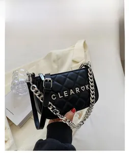 Detail of black quilted crossbody bag with silver chain strap and metal letter hardware