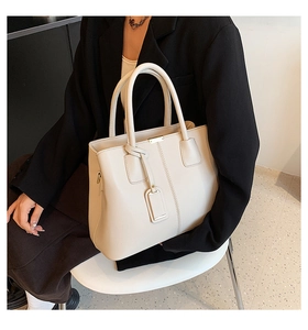 Close-up of creamy white lychee pattern tote bag with golden hardware and leather tag