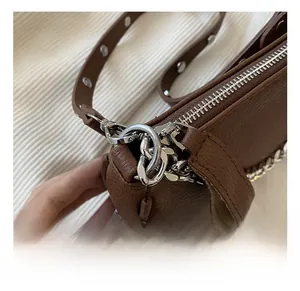 Detail of dark brown lychee grain leather bag with silver metal zipper and D-ring hardware