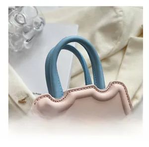 Détail d'un sac à main rose et bleu pastel avec des bords festonnés et des anses souples