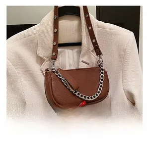 Detailed view of brown lychee leather baguette bag with silver chain and metal rivets