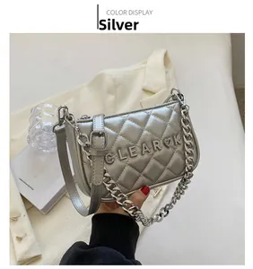 Detailed macro view of a silver quilted bag with diamond letters and a chunky chain strap