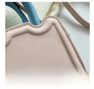 Détail du sac en cuir rose avec poignée bleue et texture de surpiqûres ondulées